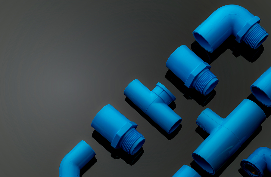Set of blue PVC pipe fittings isolated on dark background. Blue plastic water pipe. PVC accessories for plumbing. Plumber equipment. Bend and three way connection plastic pipe for water drain sewage. Fitting well means tolerance must be accurate