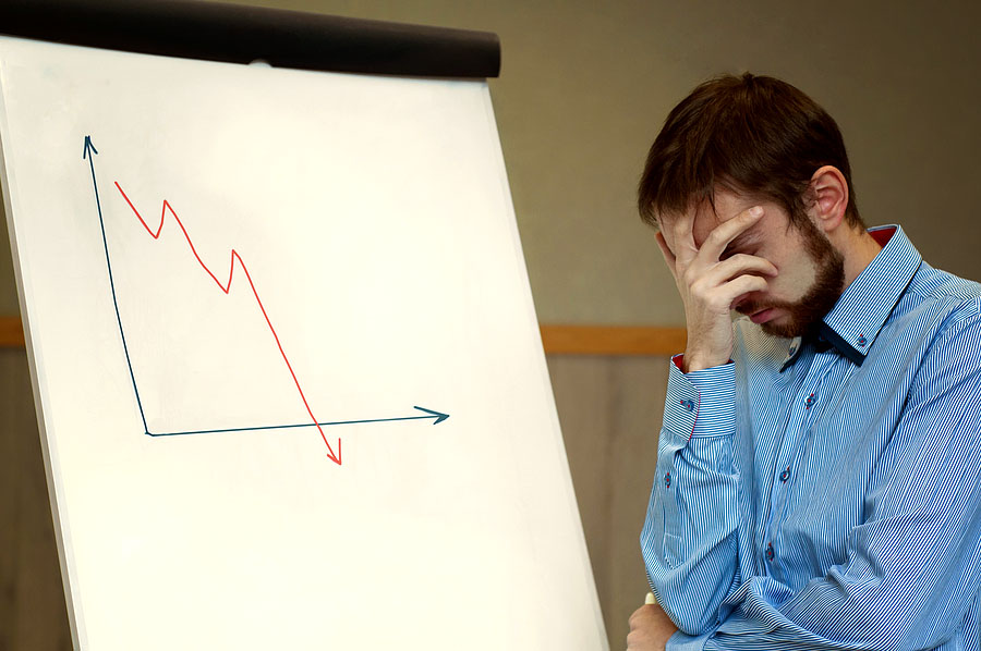 frustrated businessman next to business chart displaying a declining line graph; get things right