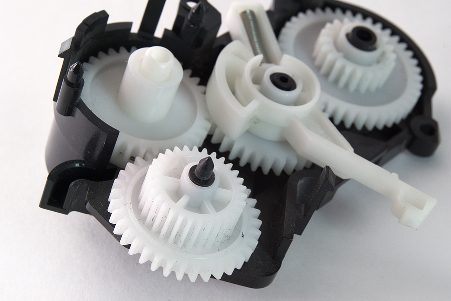 white plastic spur gears connected in complex mechanism, metal-plastic conversion benefits